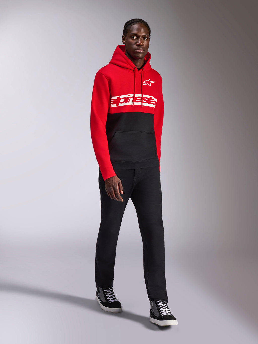 Alpinestars Parallel Hoodie, vardagliga sportkläder, röd och svart färgblockad design, med vit Alpinestars-ordlogga och stjärnlogotyp på bröstet, bärs med svarta byxor och sneakers, modern motorsportinspirerad look