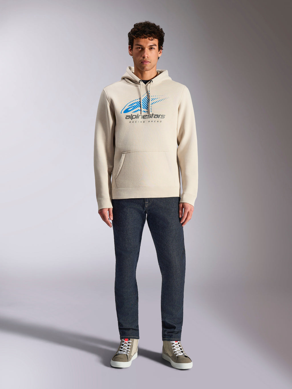 Alpinestars Pulse Hoodie, Off White, långärmad huvtröja med dragsko, blå och svart Astars Combo-logotyp med speed line fade, stylad med mörka jeans och sneakers, vardaglig motorsport-streetwear