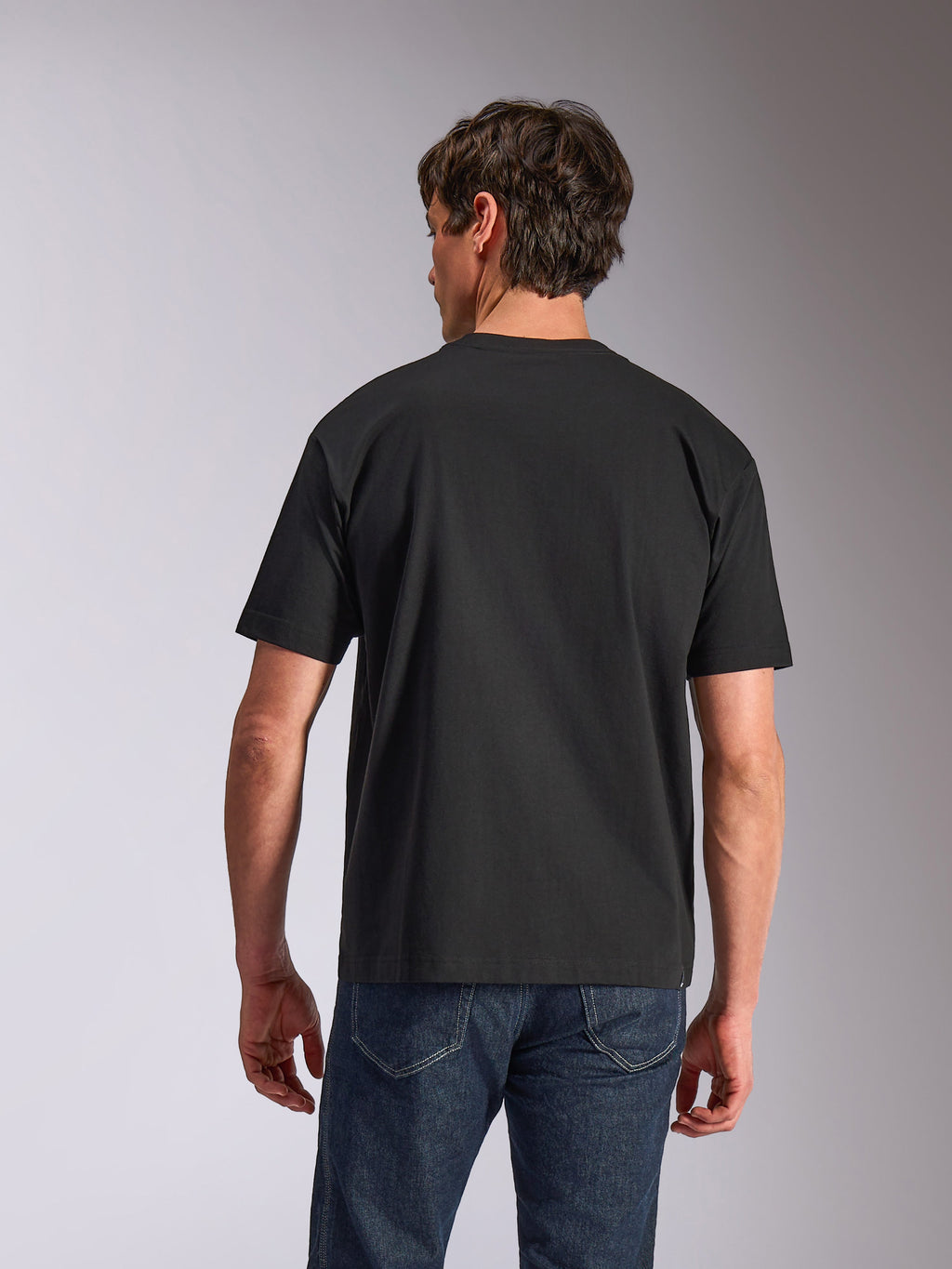 Alpinestars Aplomb Oversized CSF Tee, kortärmad t-shirt, svart, vy bakifrån, bärs av modell med blå jeans, avslappnad passform, casual sportswear