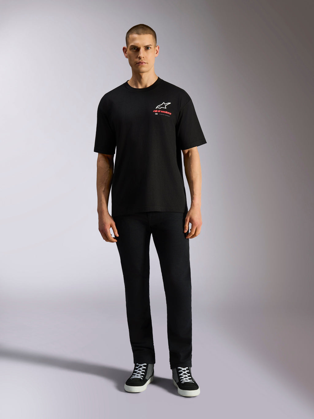 Alpinestars Overhang Oversized CSF Tee, kortärmad t-shirt, svart, vit Astars-logotyp med röd text, bärs av en modell med svarta byxor och sneakers, casual motorsport-streetwear