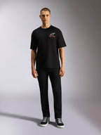 Alpinestars Overhang Oversized CSF Tee, kortärmad t-shirt, svart, vit Astars-logotyp med röd text, bärs av en modell med svarta byxor och sneakers, casual motorsport-streetwear