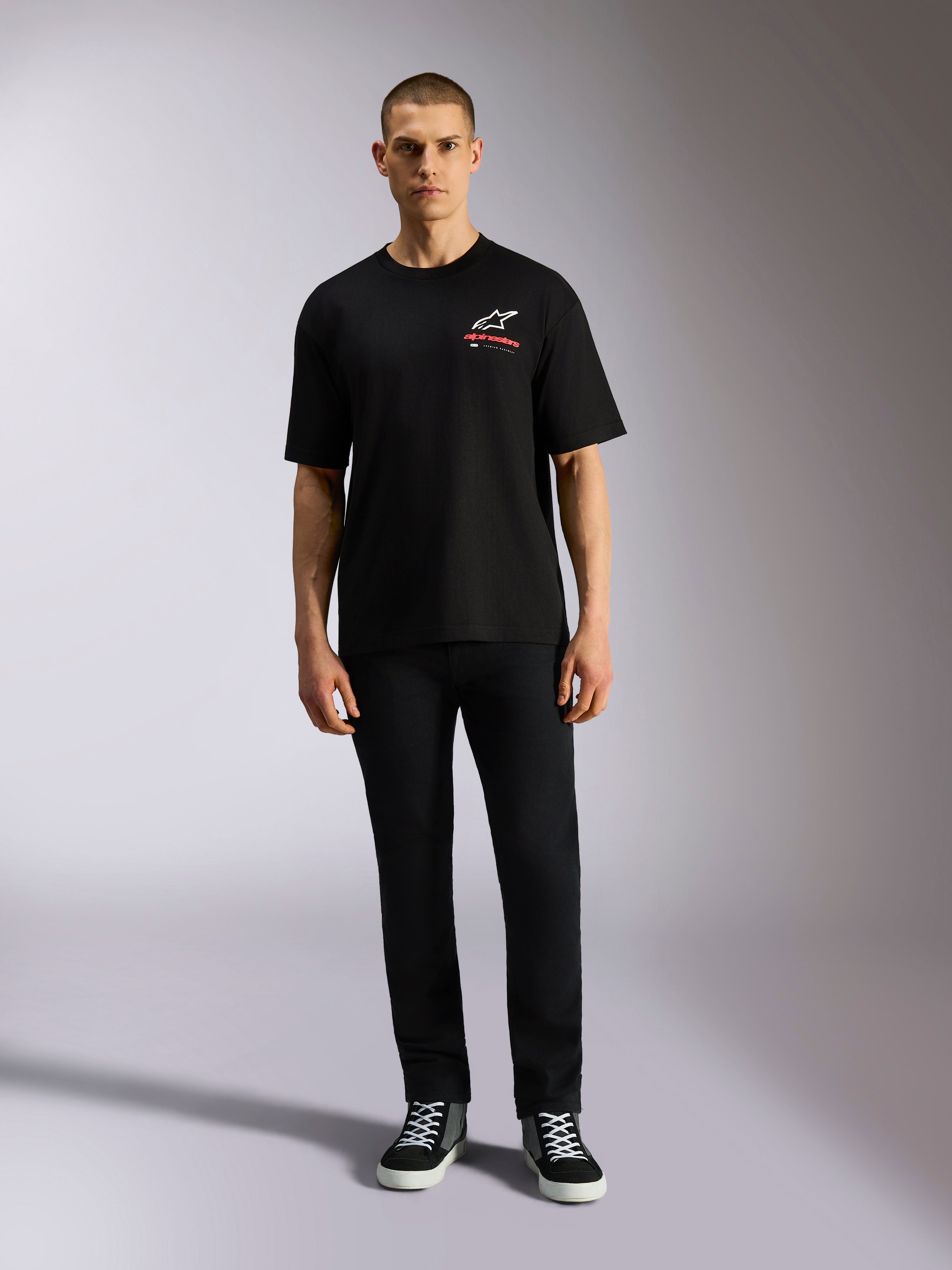 Alpinestars Overhang Oversized CSF Tee, kortärmad t-shirt, svart, vit Astars-logotyp med röd text, bärs av en modell med svarta byxor och sneakers, casual motorsport-streetwear
