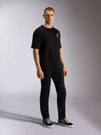 Alpinestars Overhang Oversized CSF Tee, kortärmad t-shirt, svart, med en vit och röd Astars-logotyp på framsidan, bärs av en modell med svarta byxor och sneakers, oversized avslappnad streetwear-design