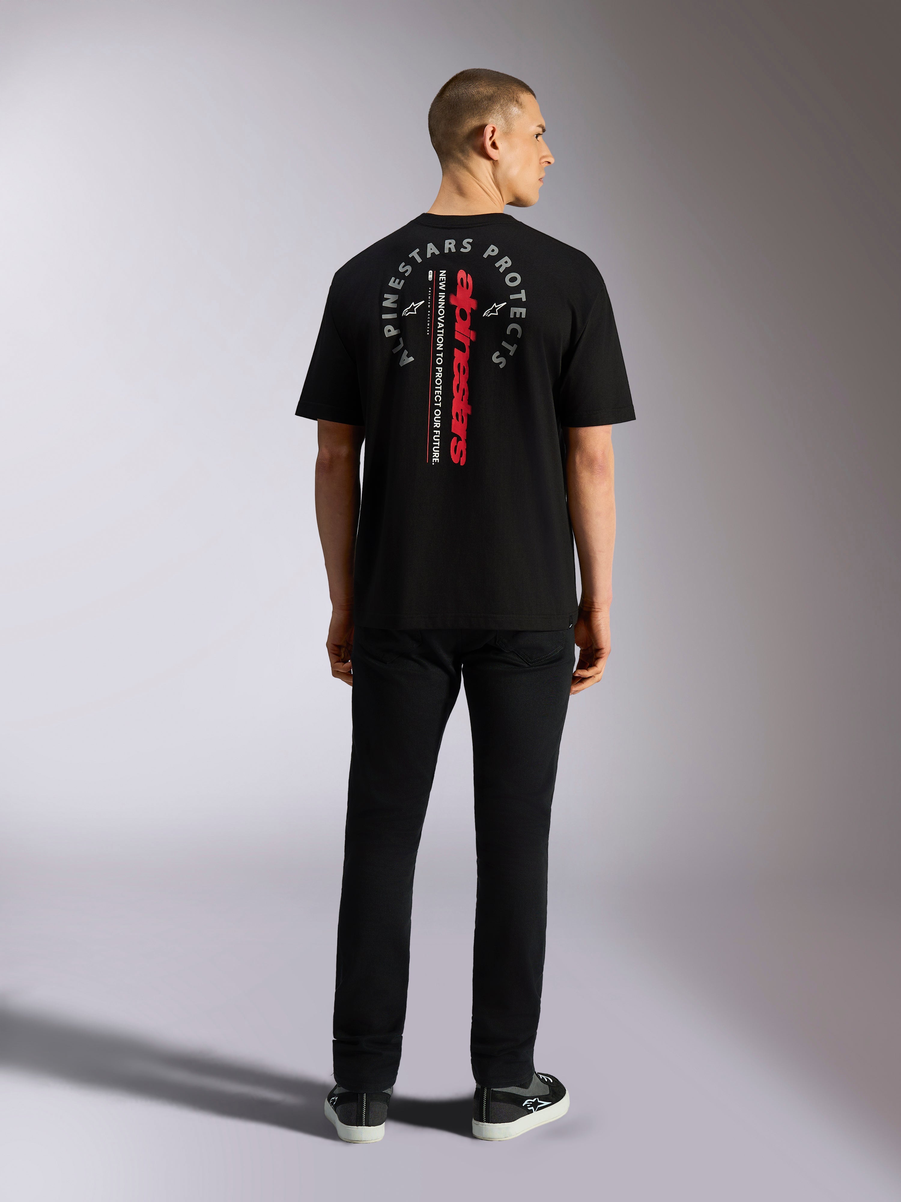 Alpinestars Overhang Oversized CSF Tee, kortärmad t-shirt, svart, med vertikalt rött Alpinestars-ordmärke och grå cirkulär grafik på ryggen, sedd bakifrån på modell, vardaglig motorsport-streetwear