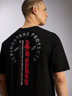 Alpinestars Overhang Oversized CSF Tee, kortärmad t-shirt, svart, vy bakifrån med vertikalt rött Alpinestars-ordmärke och cirkulär 'Alpinestars Protects'-grafik, avslappnad motorsportinspirerad streetwear