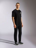 Alpinestars One Oversized CSF Tee, kortärmad t-shirt, svart, vit Astars-logotyp på bröstet, oversized passform, bärs av en manlig modell med svarta byxor och sneakers, avslappnad motorsport-inspirerad streetwear