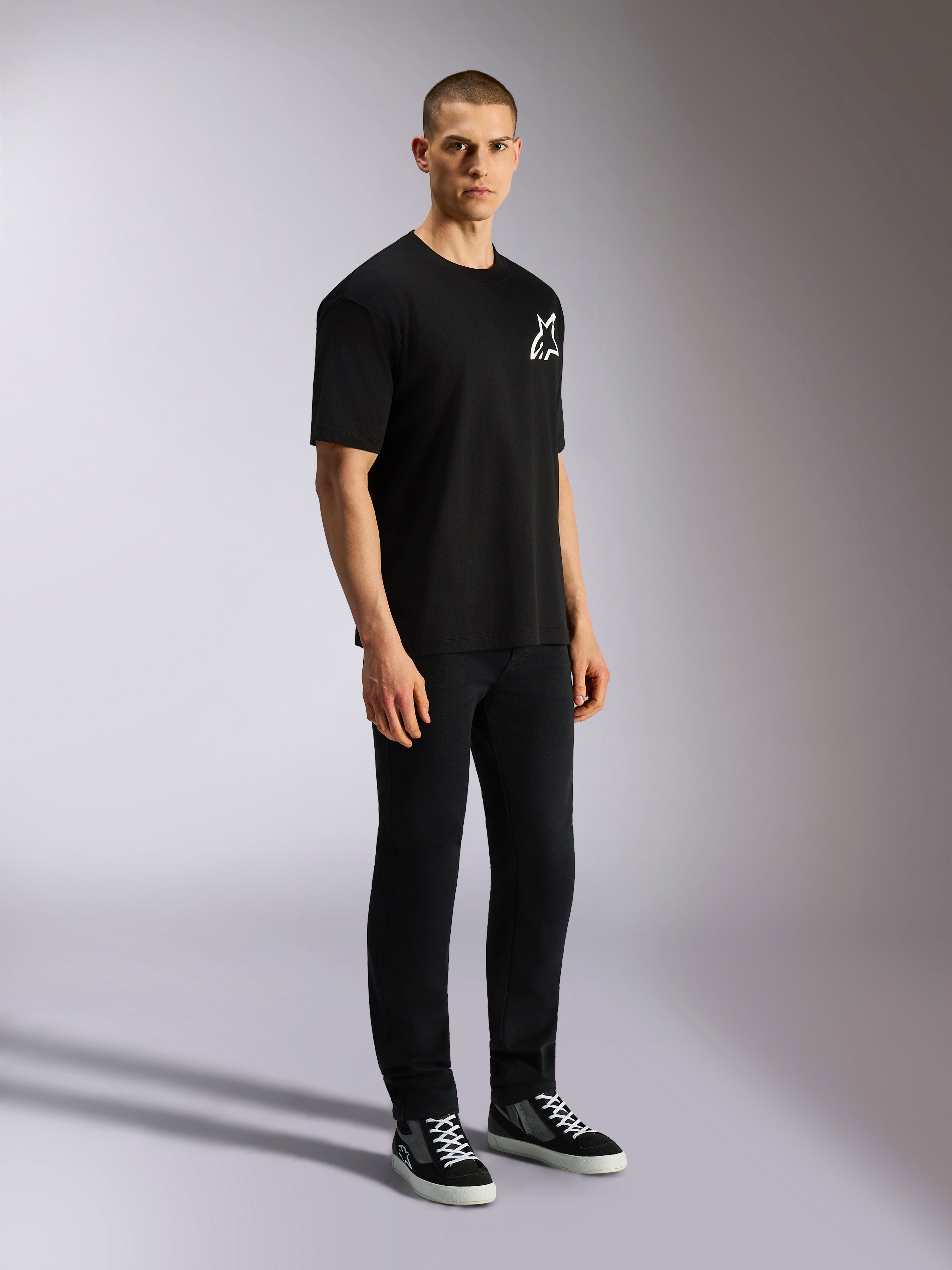 Alpinestars One Oversized CSF Tee, kortärmad t-shirt, svart, vit Astars-logotyp på bröstet, oversized passform, bärs av en manlig modell med svarta byxor och sneakers, avslappnad motorsport-inspirerad streetwear