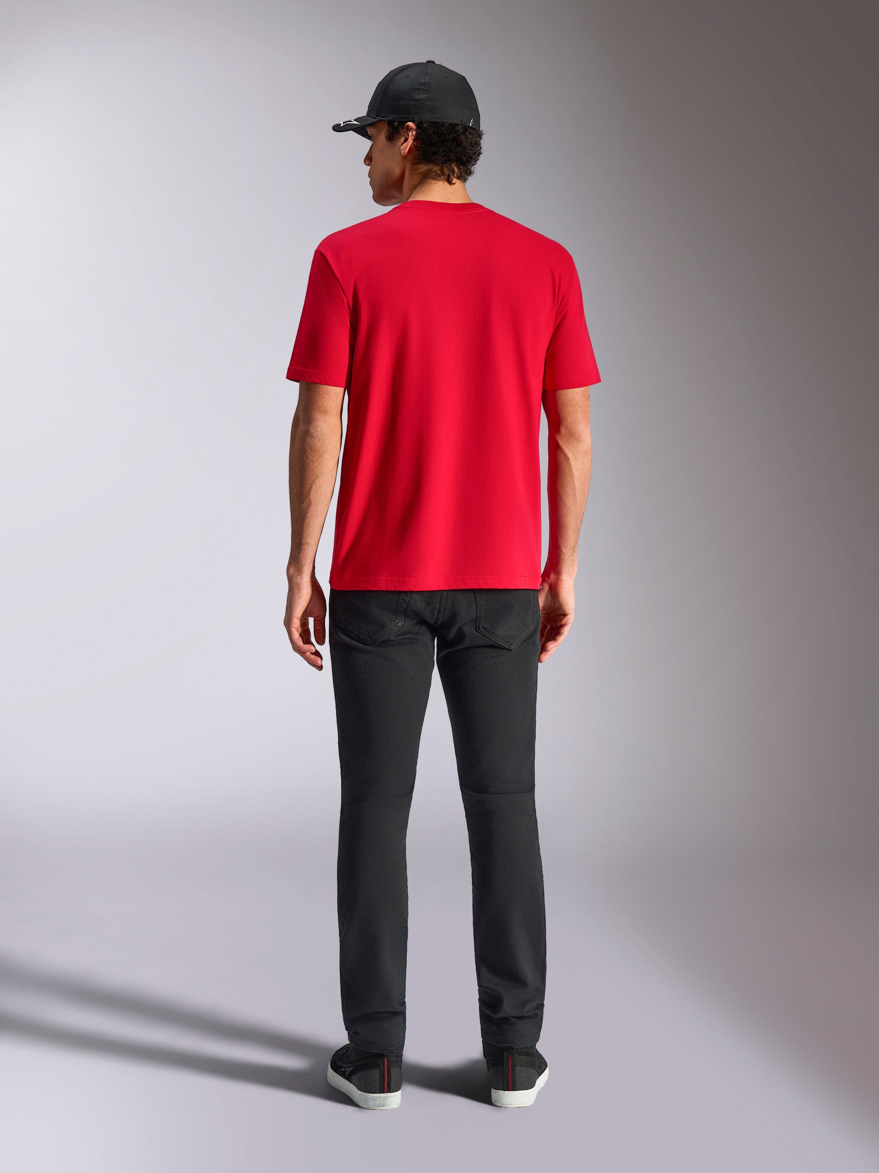 Alpinestars Noka CSF Tee, kortärmad t-shirt, röd, baksida, stylad med svarta byxor och en svart baseballkeps, vardaglig motorsportinspirerad streetwear