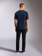 Alpinestars Noka CSF Tee, kortärmad t-shirt, marinblå, vy bakifrån av en man som bär t-shirten kombinerad med svarta byxor och sneakers, vardaglig motorsport-streetwear