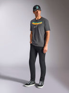 Alpinestars Ellipsoid CSF Tee, kortärmad t-shirt, kolgrå, med böjd Astars-text i färggradient och vit logotyp, bärs av modell med svarta byxor och keps, avslappnad motorsport-streetwear