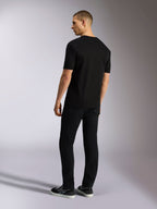Alpinestars MX CSF Tee, kortärmad T-shirt, svart, sedd bakifrån på en modell med svarta byxor, avslappnad motorsport-streetwear