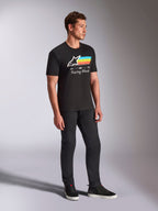 Alpinestars Trifecta CSF Tee, Short Sleeve T-Shirt, Black, white Astars logo with blue, yellow, and orange stripes and 'Racing Ahead' graphic, worn by a model with black pants and sneakers, casual motorsport-inspired lifestyle apparel