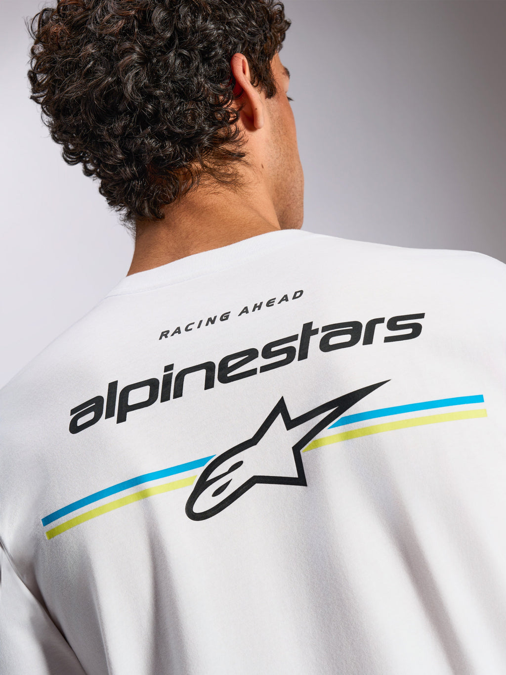 Alpinestars Lanes CSF Tee, kortärmad t-shirt, vit, grafik på ryggen med Alpinestars textlogotyp och Astars-logotyp över blåa och gula ränder, avslappnad motorsport-inspirerad streetwear