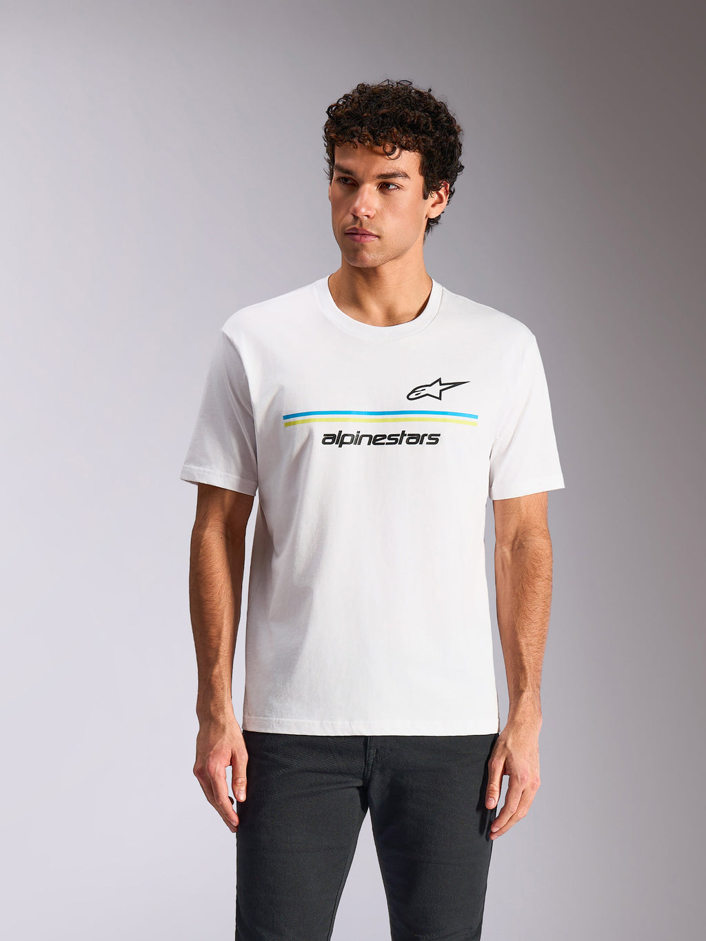 Alpinestars Lanes CSF Tee, kortärmad t-shirt, vit, med svart Astars-logotyp ovanför blå och limegröna horisontella ränder och "alpinestars"-text, bärs av modell, avslappnad motorsport-streetwear