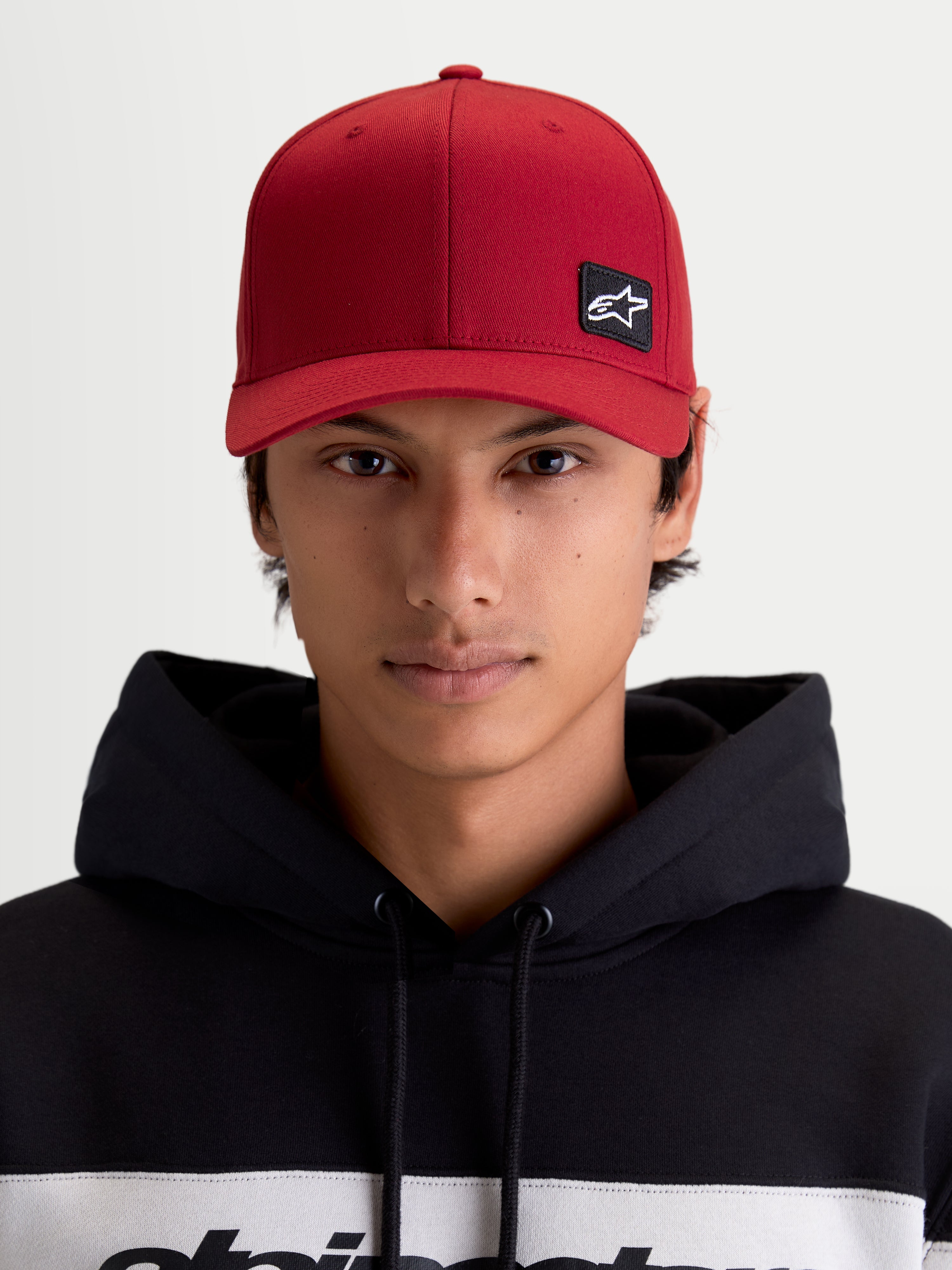 Alpinestars Pivot Hat, Dark Red Sportswear Baseball Cap, Unisex, front view on model featuring the embroidered Astars logo patch, curved bill, structured crown, and durable twill construction.