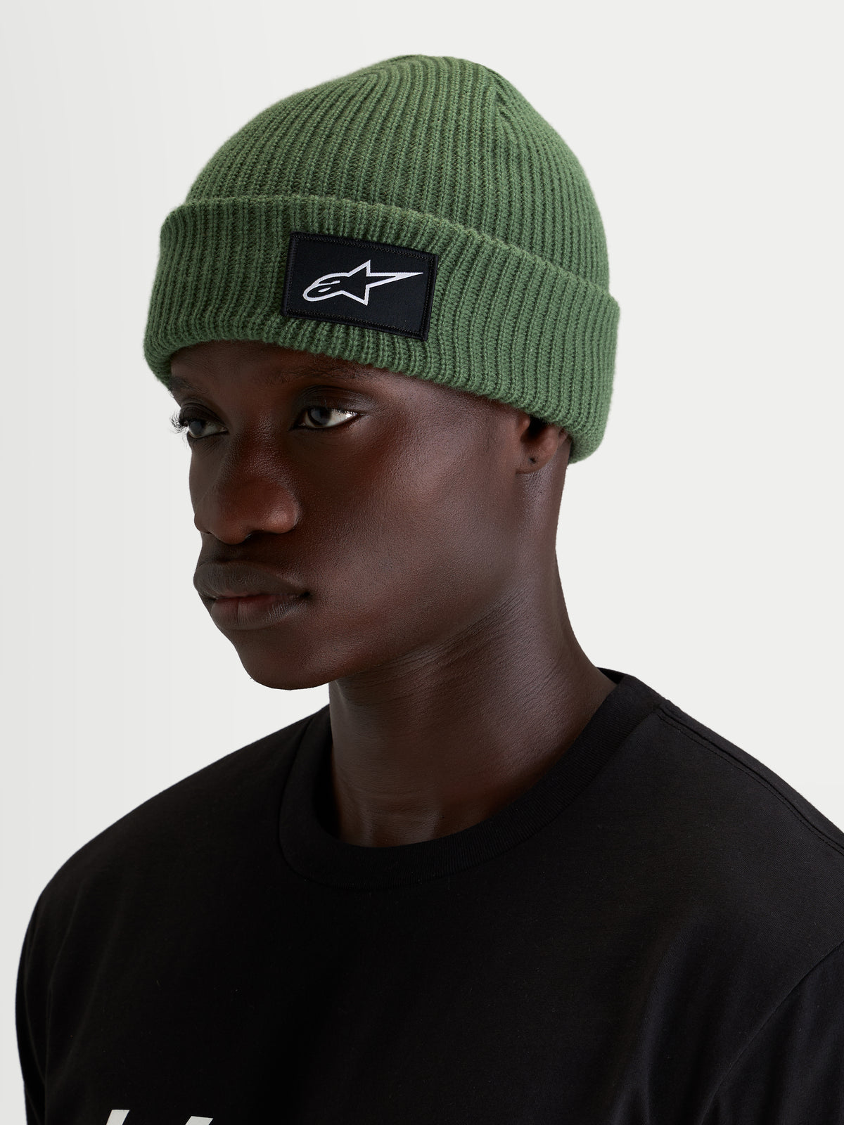Alpinestars Unload Rib Cuff Beanie, casual winter beanie in pea green, worn by a model, featuring a knit jersey stitch construction and a black and white SAstars woven front patch