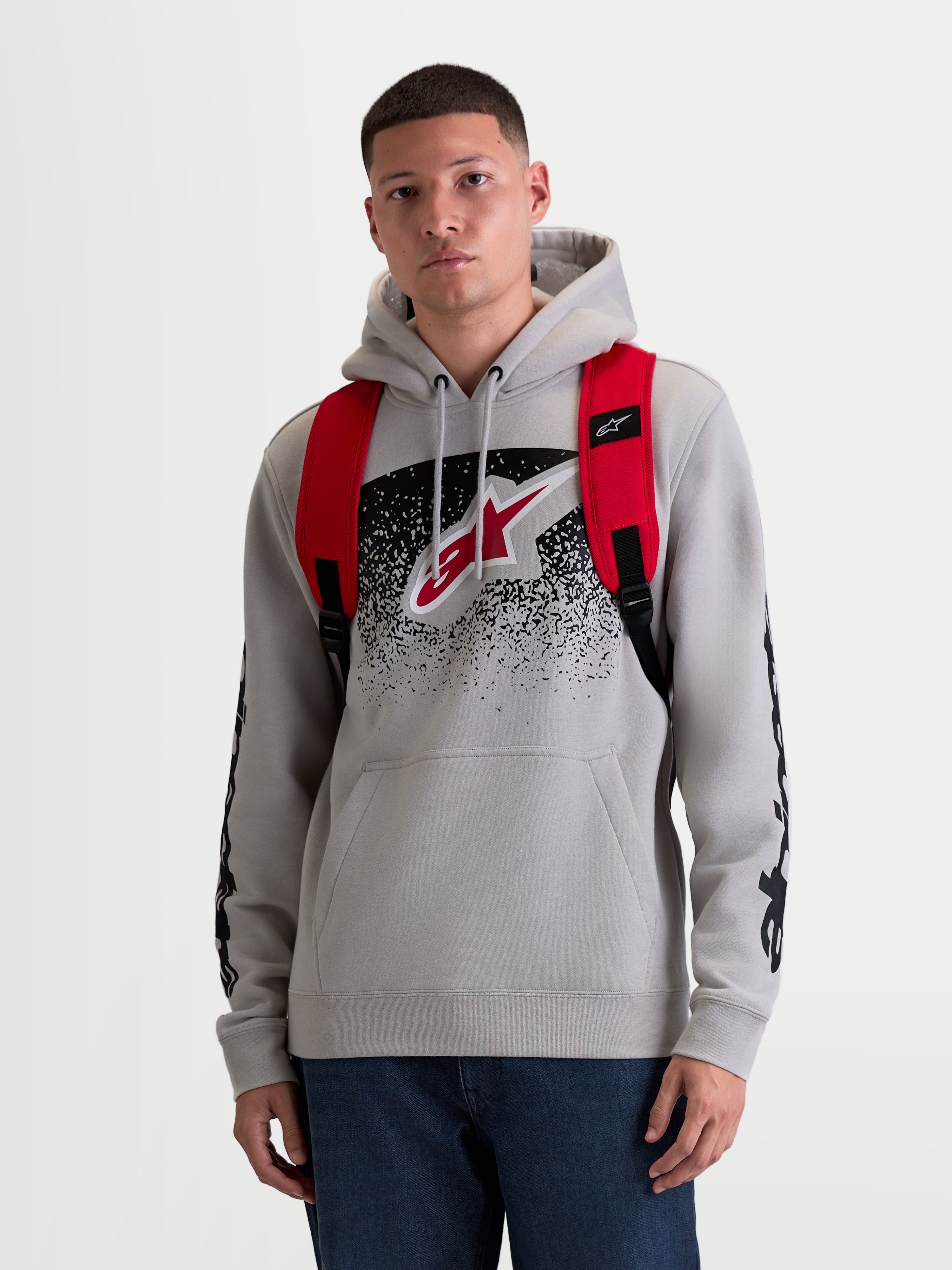 Alpinestars GFX Boss ryggsäck, 20L urban sportswear-ryggsäck för herr och dam, röd och svart, slitstark 600D polyester, frontvy på modell med justerbara axelremmar i luftmesh och upphöjd silikonlogotyp.