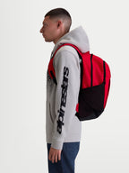 Alpinestars GFX Boss ryggsäck, röd och svart 20L sportryggsäck i hållbar 600D polyester med sidofickor i mesh för vattenflaskor och vadderade axelremmar, visas på modell för urban pendling och vardagsbruk.