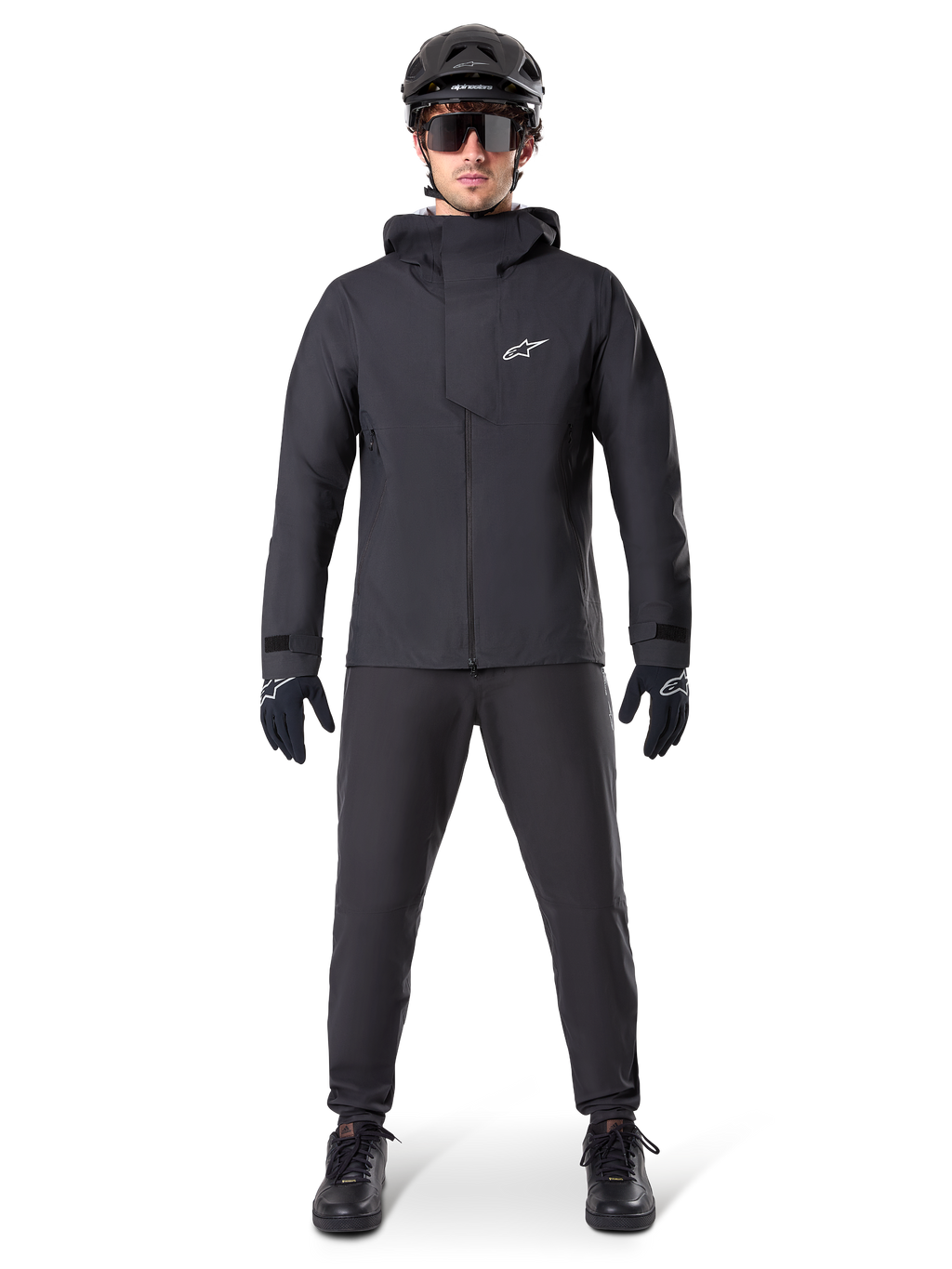 Alpinestars A-Dura Elite vattentät jacka, svart, bärs med matchande cykelbyxor och handskar, svart hjälm och solglasögon, med en vit Astars-logotyp på bröstet, högpresterande teknisk design för mountainbike