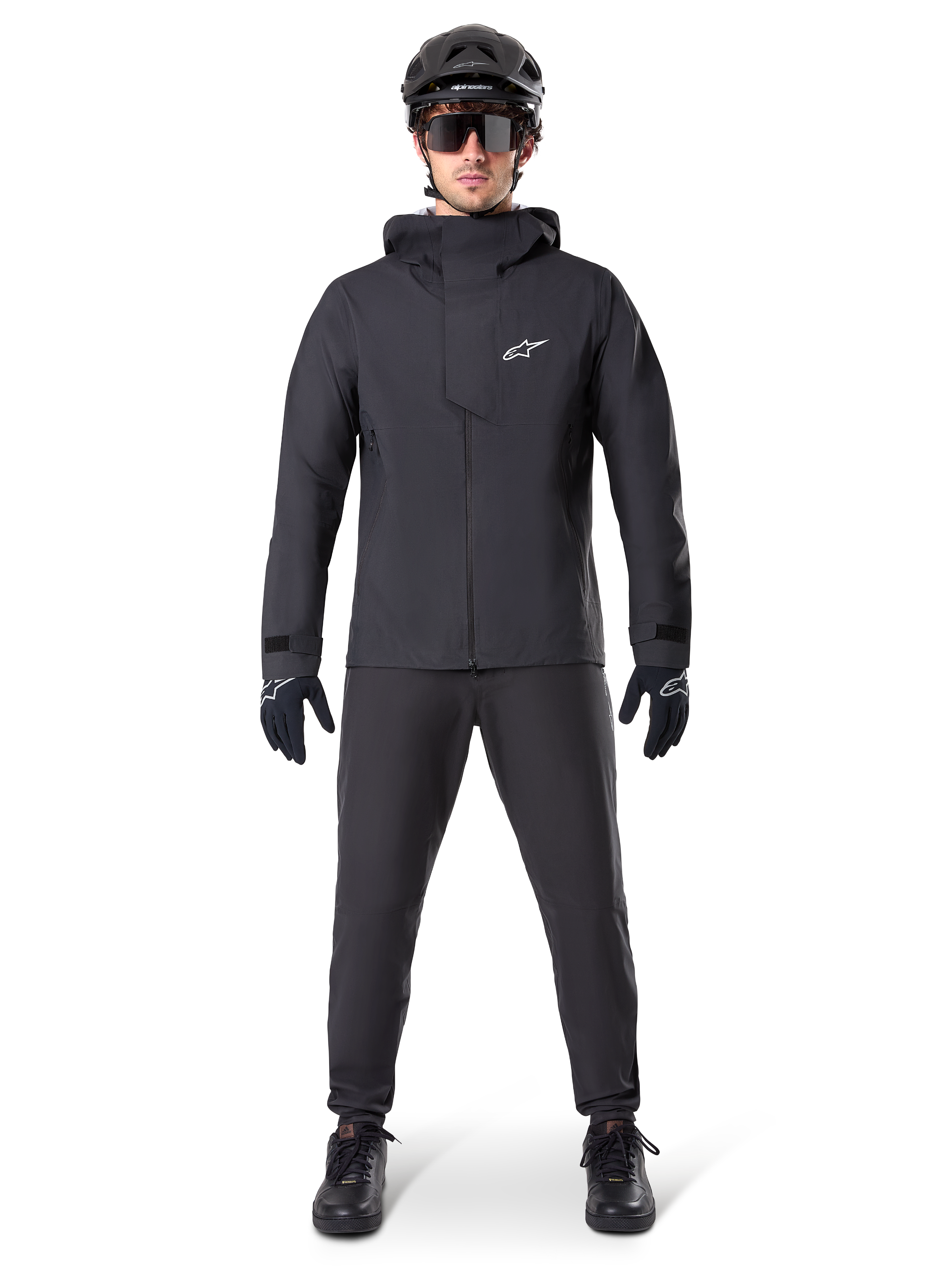 Alpinestars A-Dura Elite vattentät jacka, svart, bärs med matchande cykelbyxor och handskar, svart hjälm och solglasögon, med en vit Astars-logotyp på bröstet, högpresterande teknisk design för mountainbike