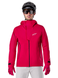Alpinestars A-Dura Elite Waterproof Jacket, regnjacka för mountainbike, Red Fluo, hög krage med vit Alpinestars-logotyp, svarta dragkedjedetaljer, bärs med matchande handskar och svart cykelhjälm, teknisk vattentät cykelutrustning
