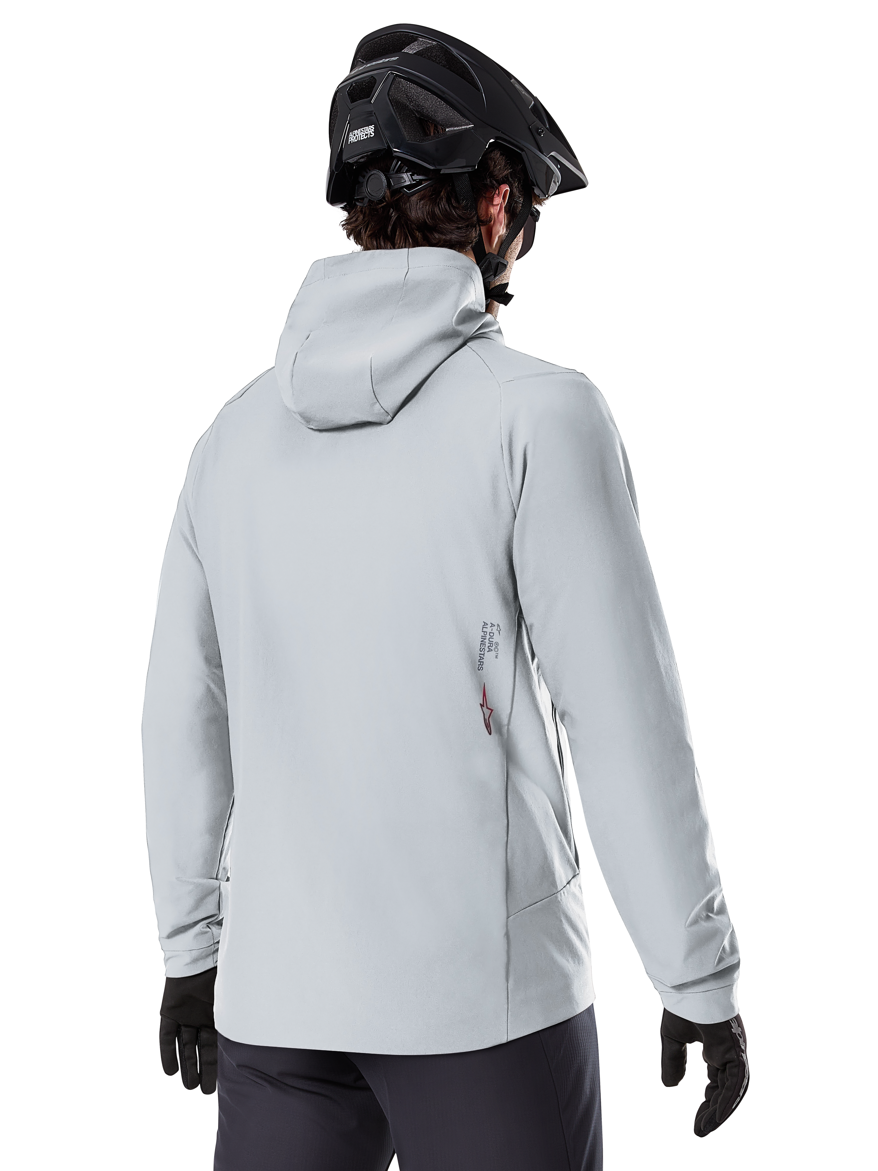 Alpinestars A-Dura Thermal Jacka, Titaniumgrå, vy bakifrån av en cyklist som bär den isolerade jackan med huva, kombinerad med en svart MTB-hjälm och svarta handskar, med en liten Alpinestars-logotyp på nedre delen av ryggen, designad för mountainbiking i kallt väder.