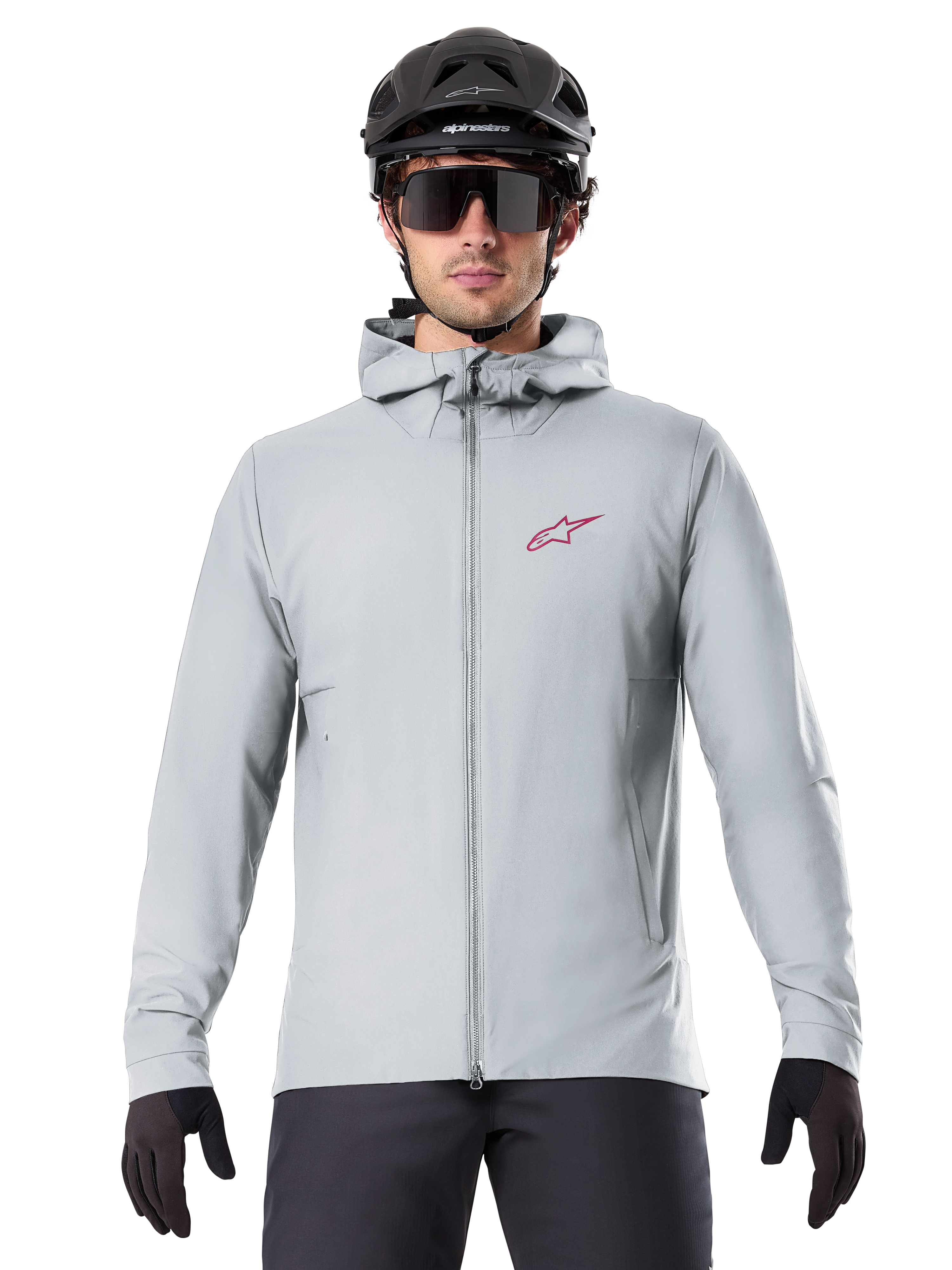 Alpinestars A-Dura Thermal Jacka i Titanium, ljusgrå cykeljacka med huva, röd stjärnlogotyp på bröstet, bärs av en cyklist med svart MTB-hjälm, solglasögon och handskar, isolerad utrustning för mountainbike