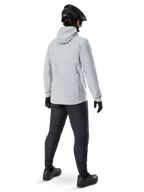 Alpinestars A-Dura Thermal Jacket i Titanium, vy bakifrån av en manlig cyklist i en ljusgrå termojacka med huva, matchad med svart MTB-hjälm, svarta handskar och mörkgrå byxor, funktionell utrustning för mountainbikecykling.