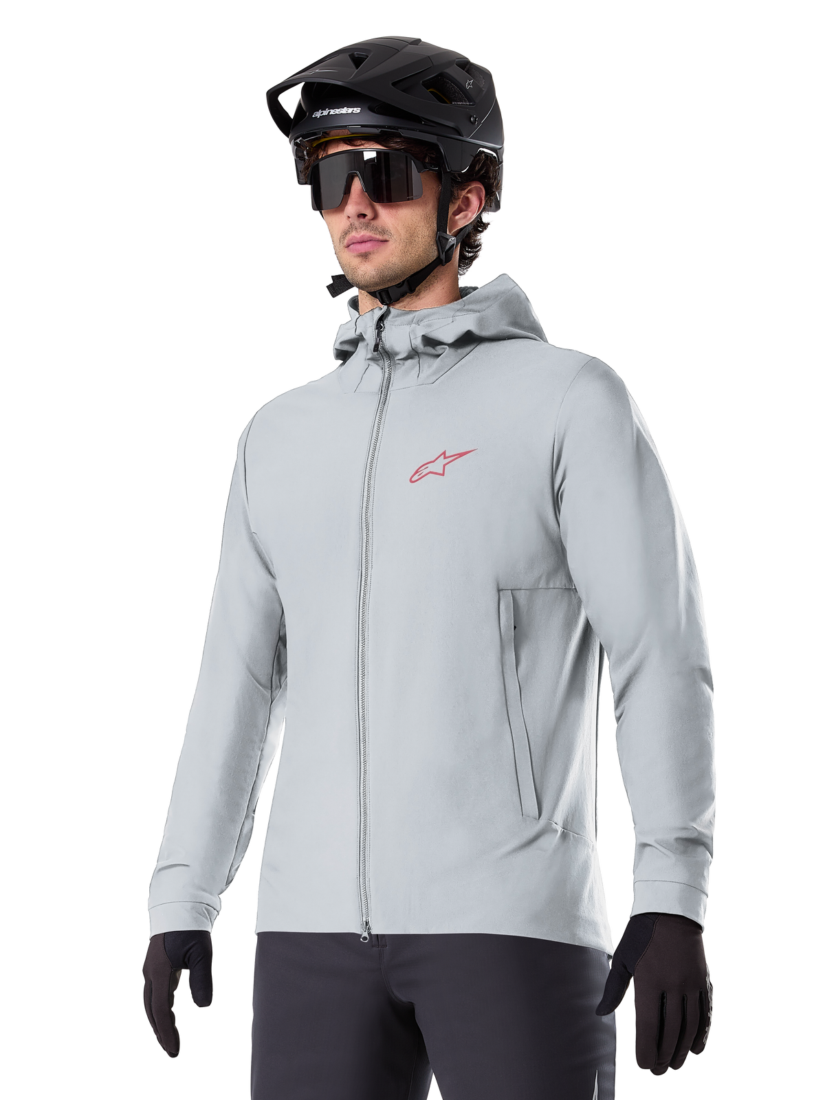 Alpinestars A-Dura Thermal Jacket, ljusgrå isolerad cykeljacka, design med huva och en liten röd logotyp, bärs med svart hjälm och handskar, tekniska mountainbikekläder för cykling i kallt väder