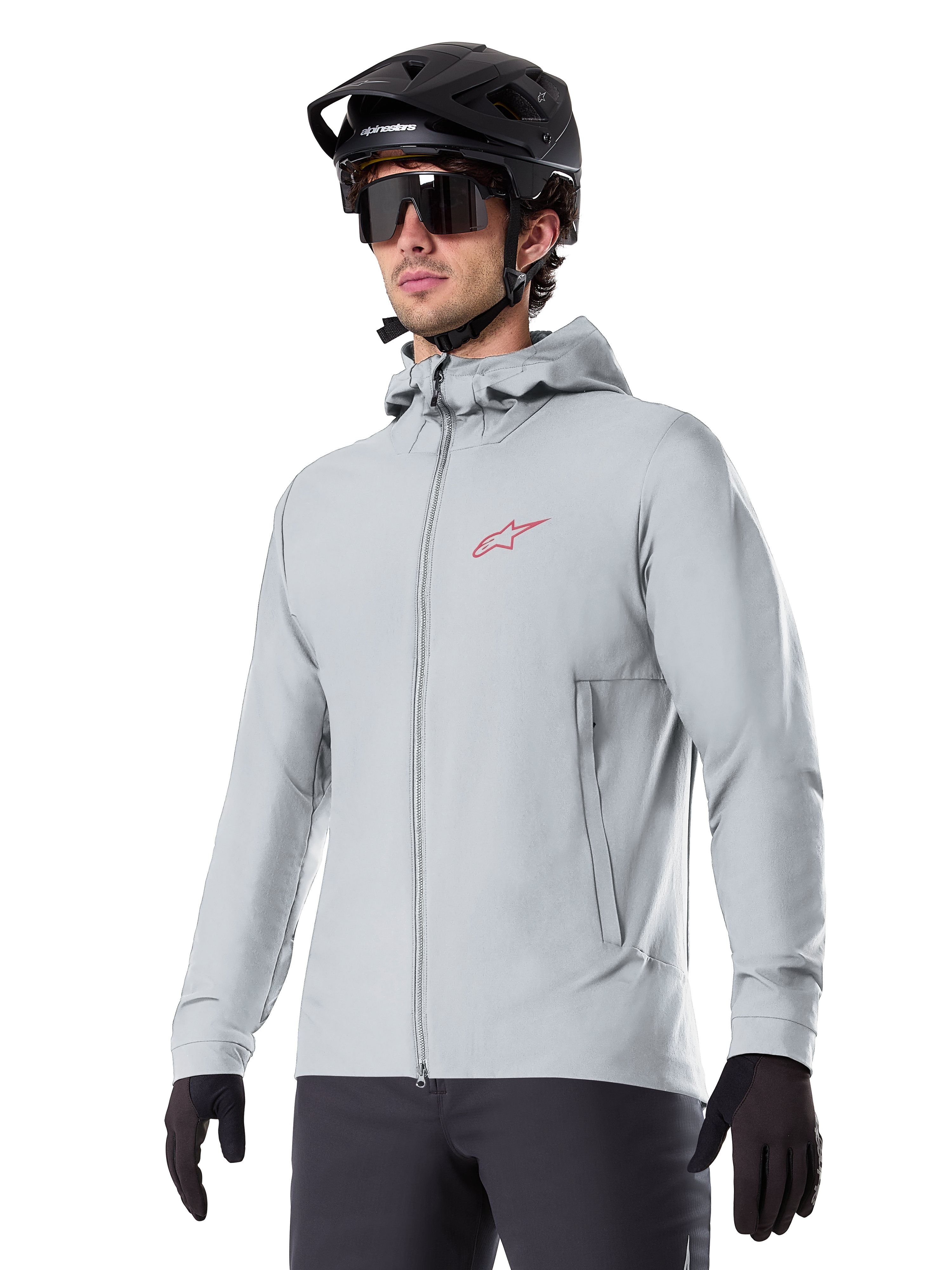 Alpinestars A-Dura Thermal Jacket, ljusgrå isolerad cykeljacka, design med huva och en liten röd logotyp, bärs med svart hjälm och handskar, tekniska mountainbikekläder för cykling i kallt väder