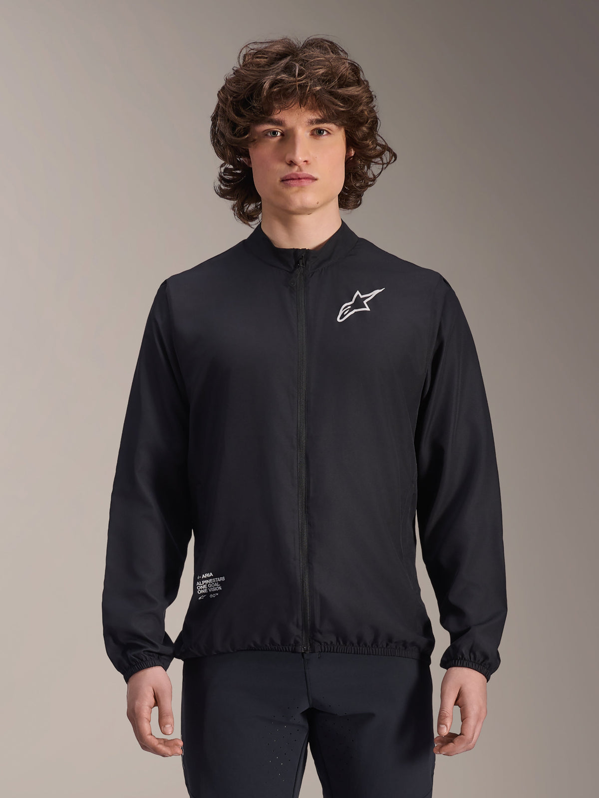 Alpinestars A-Aria Windbreaker-jacka, svart, lättviktig cykeljacka med vit Astars-logotyp på bröstet och branding nere till höger, hel dragkedja fram, hög krage, elastiska muddar och nederkant, prestandapassform för utomhussporter