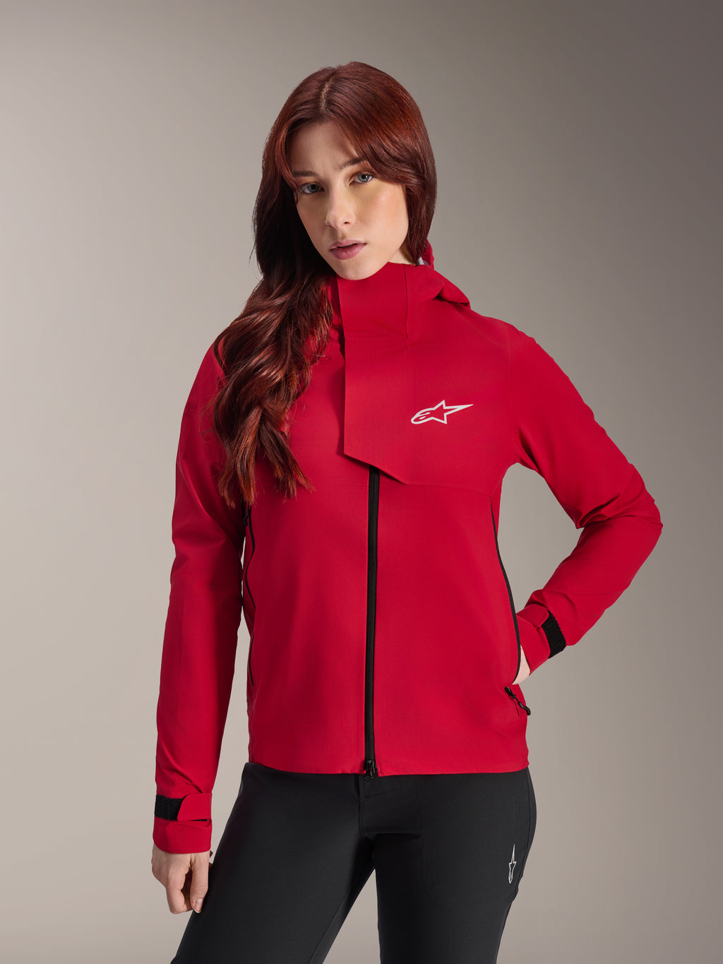 Alpinestars Stella A-Dura Elite Vattentät Jacka, mountainbikejacka för dam, Red Fluo, med en vindslå framtill med en vit Alpinestars-logotyp, hög krage och justerbara manschetter, bärs med svarta byxor för en teknisk look
