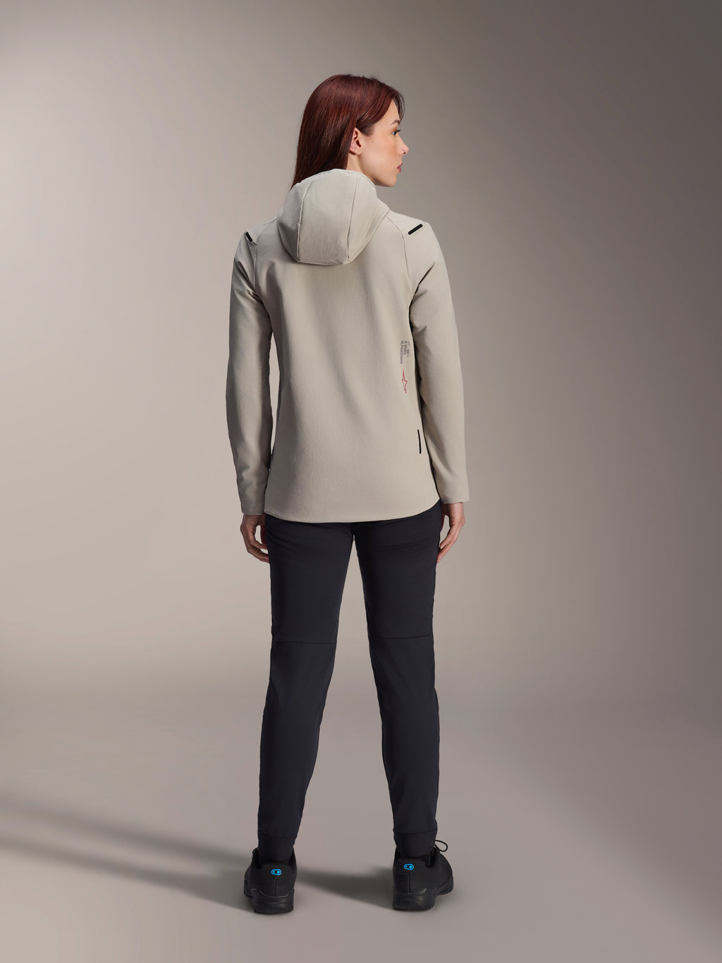 Alpinestars Stella A-Dura Thermal Jacket för dam, Titaniumgrå, baksida bärs med svarta byxor, med fleecefodrad isolerad huva och en liten röd logotyp, funktionell och snygg mountainbikejacka för cykling i kallt väder.
