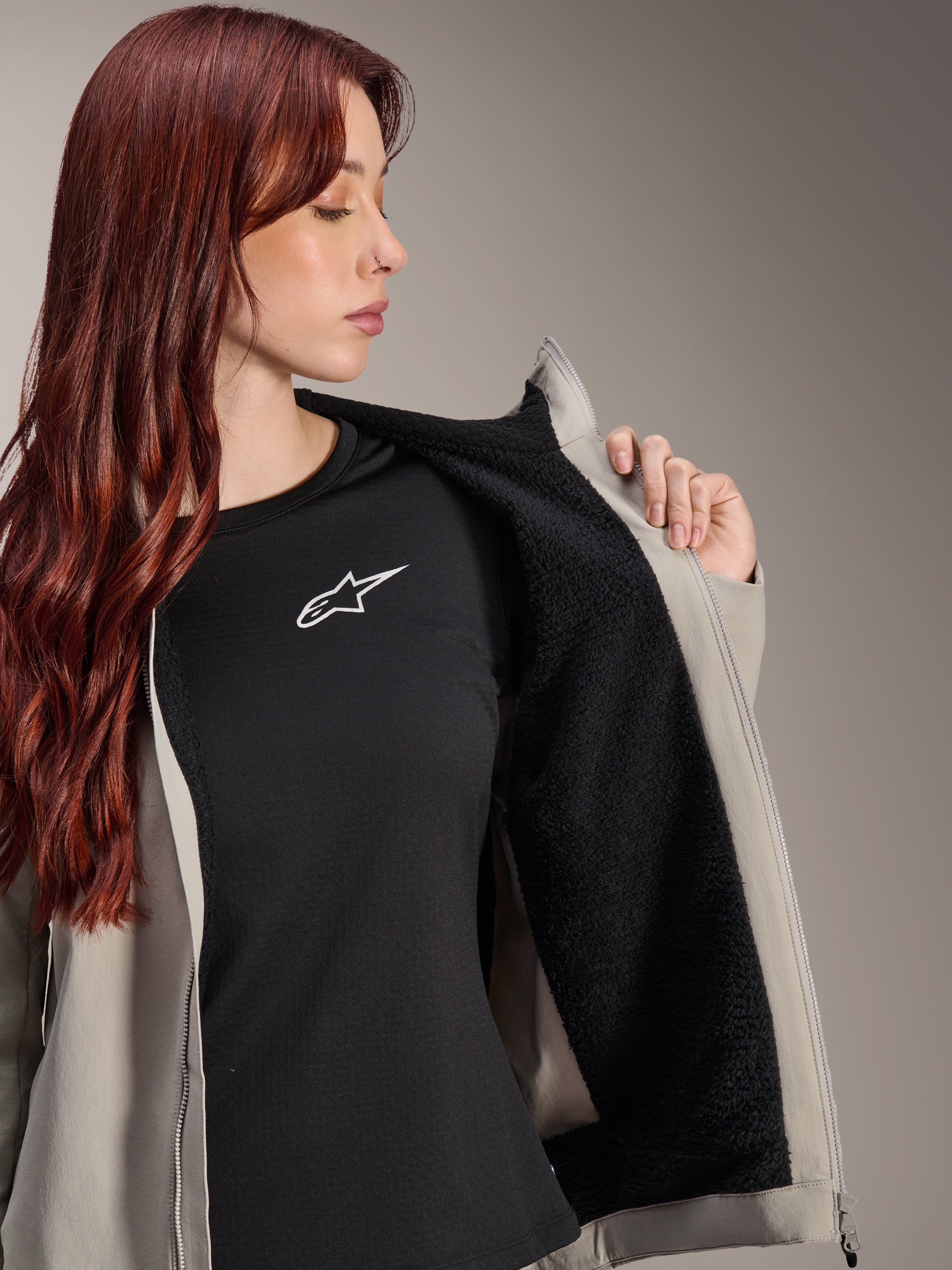 Kvinna som bär Alpinestars Stella A-Dura Thermal Jacket i Titanium, visar det svarta texturerade fleecefodret, bärs över en svart t-shirt med vit stjärnlogotyp, lätt mountainbikejacka för kalla förhållanden