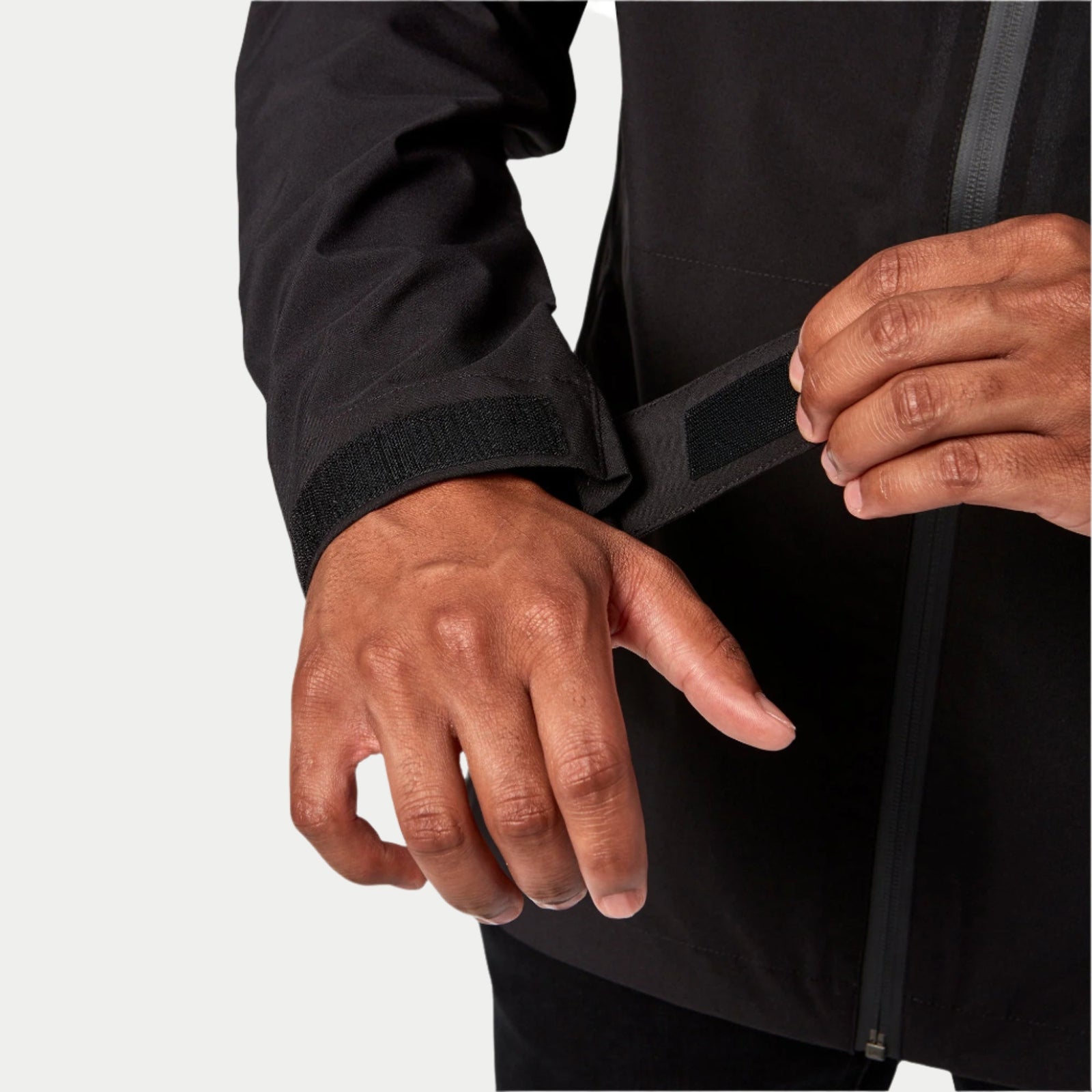 Alpinestars Primary Jacket in Black, close-up detail of adjustable velcro cuff strap, softshell wind-resistant material, showing front zipper and technical fabric construction