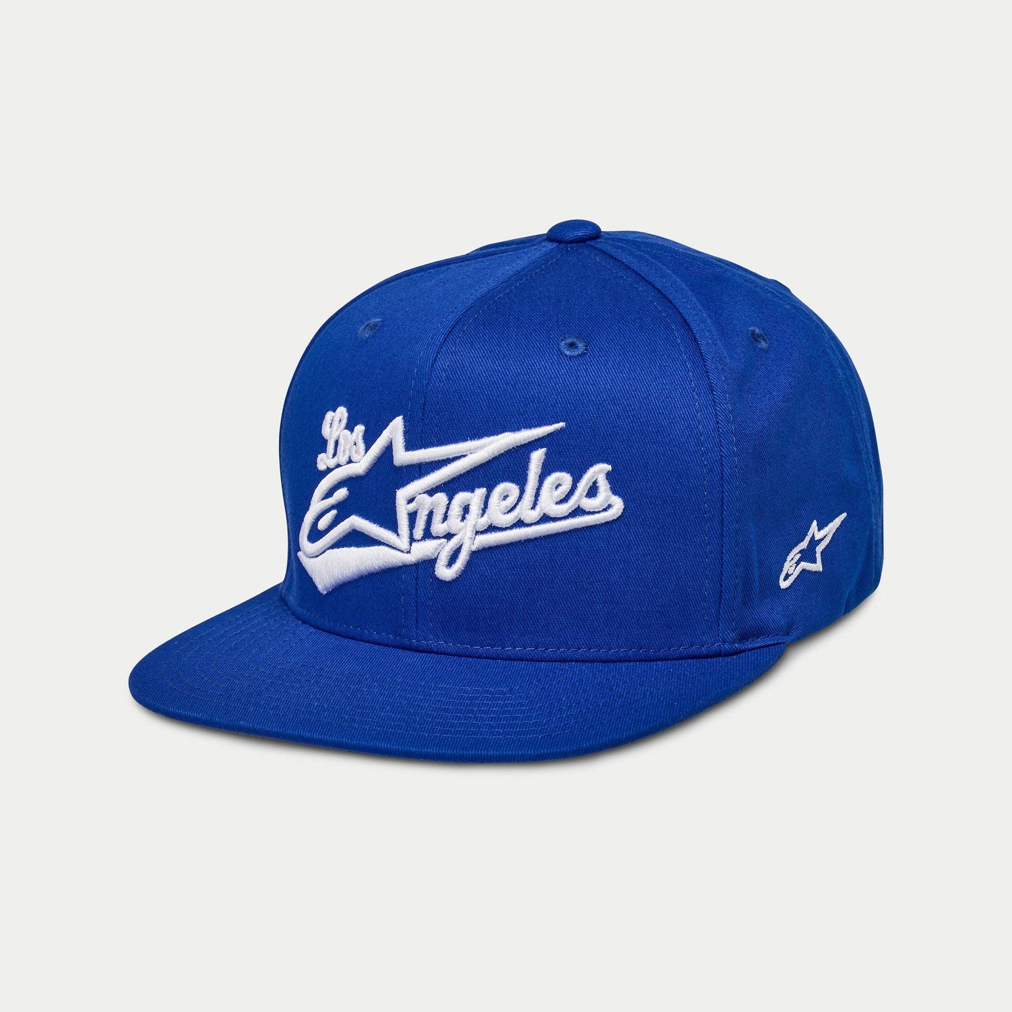 Alpinestars Los Angeles Hat, blå snapback-keps med platt skärm, vitt 3D-broderat 'Los Angeles' i atletiskt typsnitt, Ageless-logotyp på sidan, strukturerad krona, vardaglig motorsport-inspirerad huvudbonad