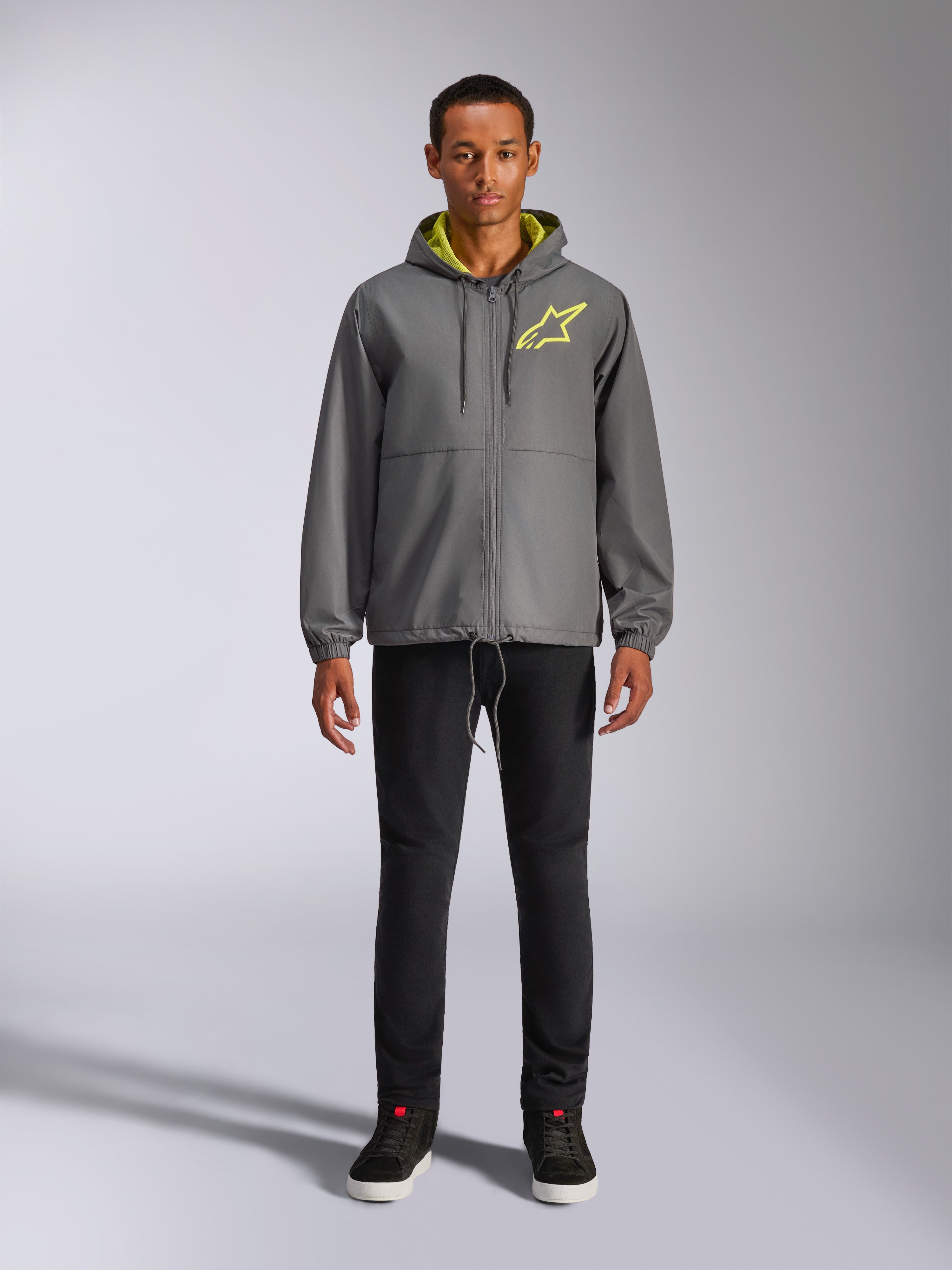 Alpinestars Speeder Chromium vindjacka, mörkgrå jacka med huva med varselgult foder och logotyp på bröstet, hel dragkedja framtill, elastiska muddar, avslappnat motorsport-inspirerat streetwear
