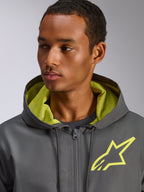Alpinestars Speeder Chromium vindjacka, mörkgrå med varselgula detaljer, med en gul stjärnlogotyp på bröstet och matchande meshfoder i huvan, lätt och ledig vindjacka