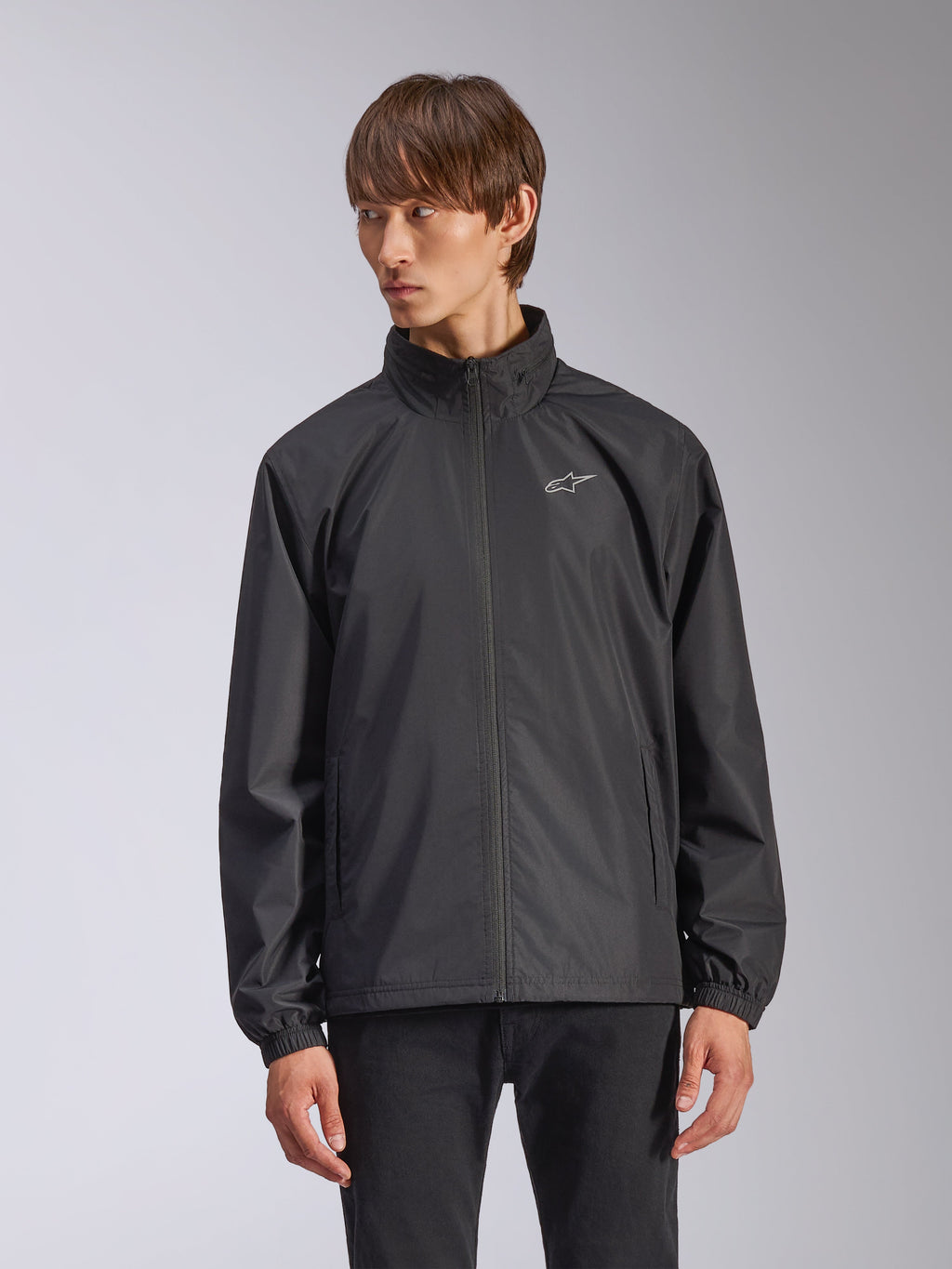 Alpinestars Overhaul Racer Jacket, svart regnskaljacka för herr, med hög krage och hel dragkedja framtill, liten vit logotyp på bröstet, elastiska muddar, slätt vattenavvisande material, minimalistisk motorsportinspirerad design