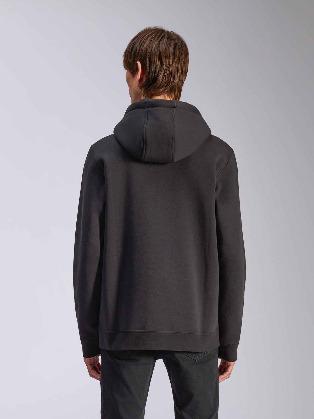 Alpinestars Harken Hoodie, svart, ryggvy av manlig modell som bär en avslappnad fleece-pullover, ribbade muddar och nederkant, modernt motorsportinspirerat streetwear