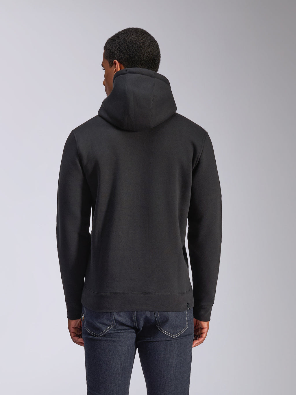 Alpinestars Blaze V3 Hoodie, rear view of black pullover fleece hoodie, casual streetwear, featuring ribbed cuffs and hem, jersey-lined hood, worn with dark blue jeans