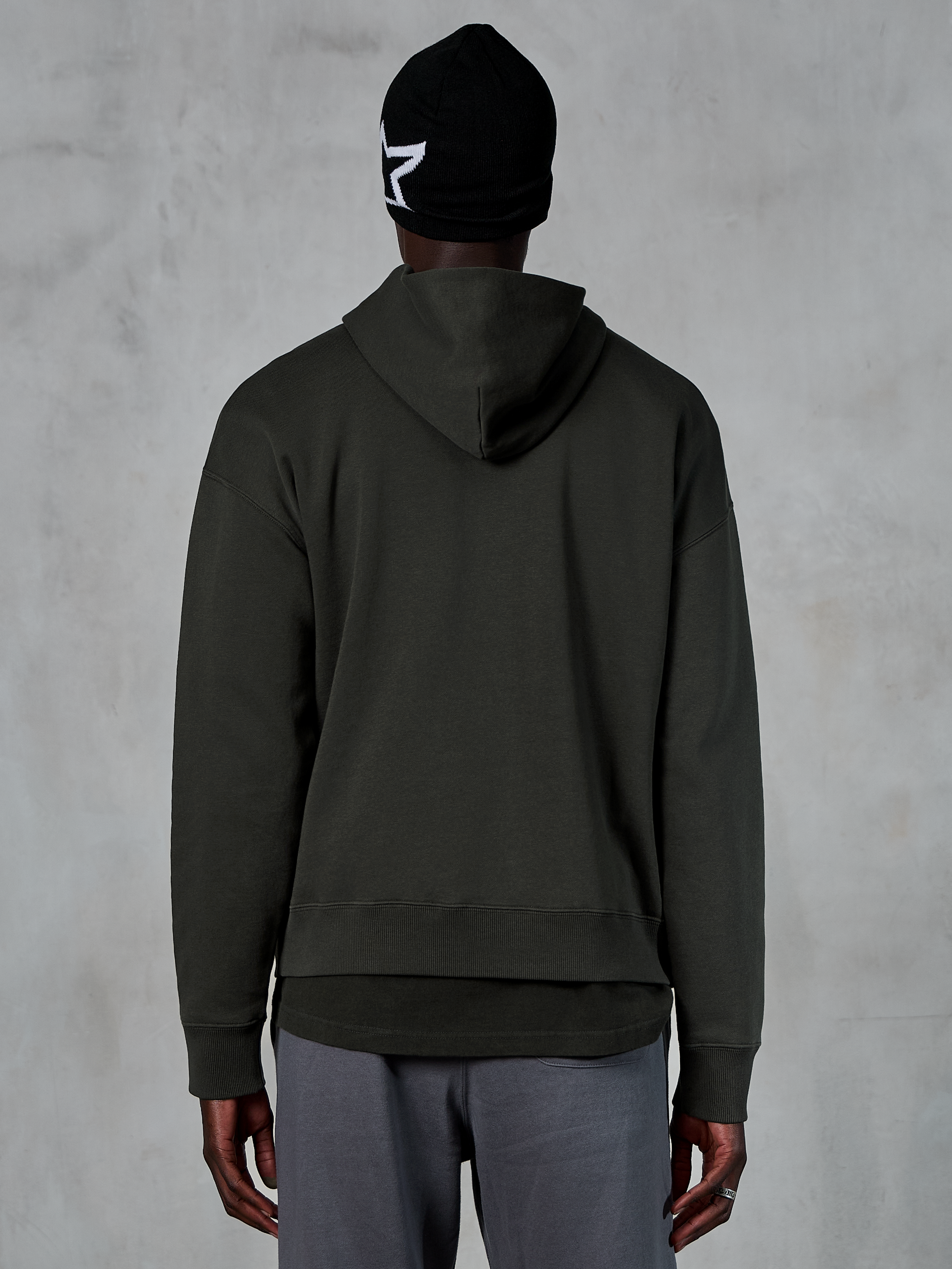 Alpinestars Essentials Ageless Hoodie, baksida, Off Black, casual streetwear, modell bär svart mössa med vit stjärnlogotyp och grå byxor, premiumfleece med stentvättad finish