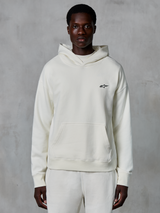 Alpinestars Essentials Ageless Hoodie, off-white, bärs av en manlig modell, liten svart logotyp på bröstet, känguruficka fram, långa ärmar, avslappnat motorsportinspirerat streetwear
