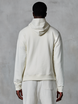 Alpinestars Essentials Ageless Hoodie, off-white pullover-huvtröja, sedd bakifrån på modell, ren minimalistisk design, matchande vardagsbyxor, avslappnad passform för vardagskomfort