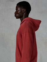 Alpinestars Essentials Ageless Zip Hoodie, tegelröd, sidoprofil av en man i en huvtröja med dragkedja och avslappnad passform, liten svart stjärnlogotyp på bröstet, premium stentvättad fleece, avslappnad motorsportinspirerad streetwear