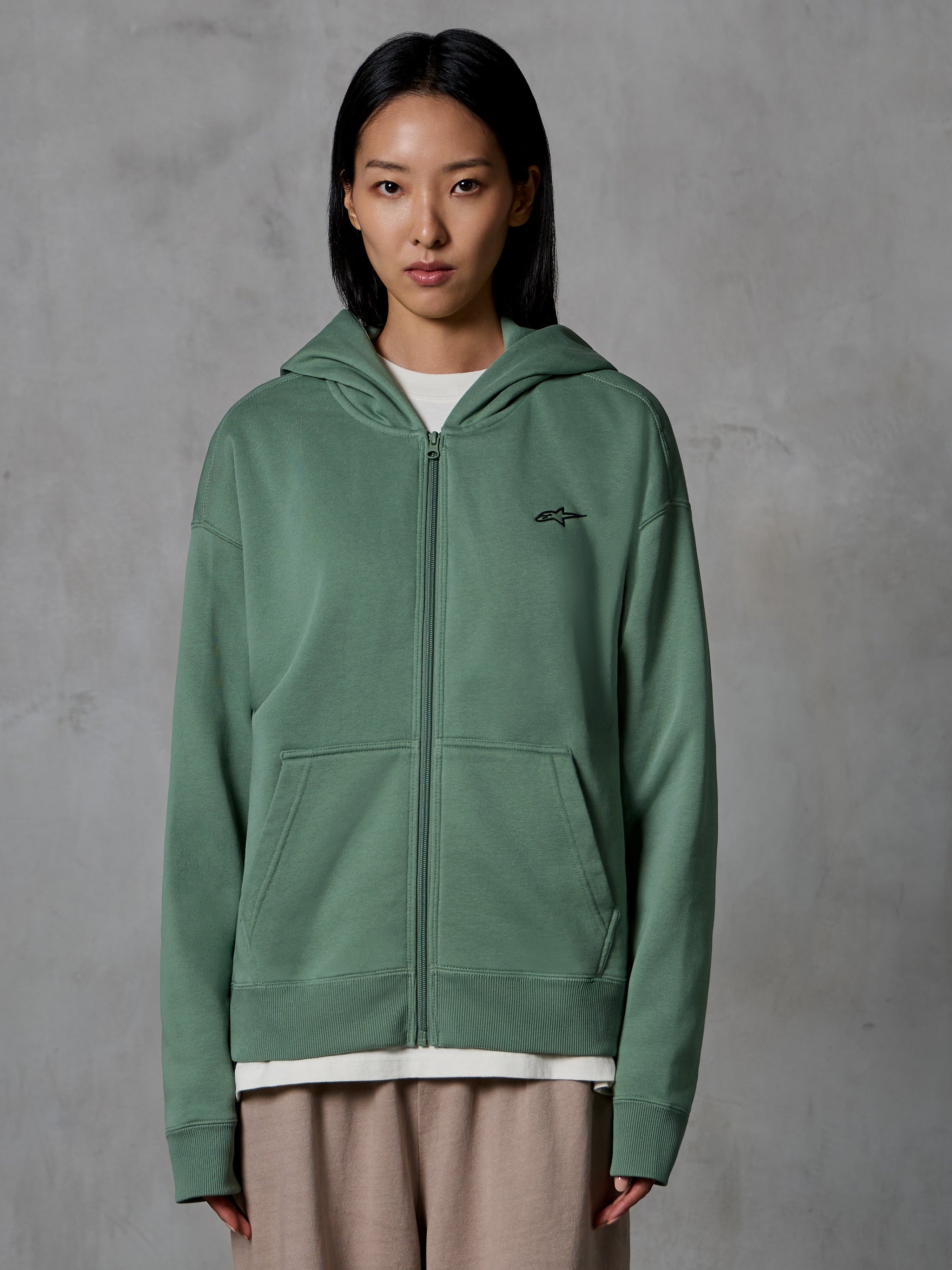 Alpinestars Essentials Ageless Zip Hoodie, Cactus Green, casual streetwear worn by female model, zip-up fleece sweatshirt with small black logo on the chest, front pockets, relaxed fit for everyday wear