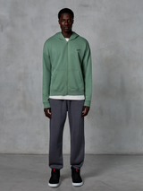 Alpinestars Essentials Ageless Zip Hoodie, Zip-up Hoodie, Cactus Green, worn by a model with dark grey joggers and black sneakers, featuring a small black Alpinestars logo on the chest, relaxed fit, casual streetwear.