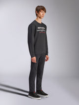 Alpinestars Bettern Crew Sweatshirt, black crewneck pullover, white alpinestars logo with 'RACING AHEAD' in red on the chest, paired with black pants and sneakers, casual motorsport-inspired streetwear