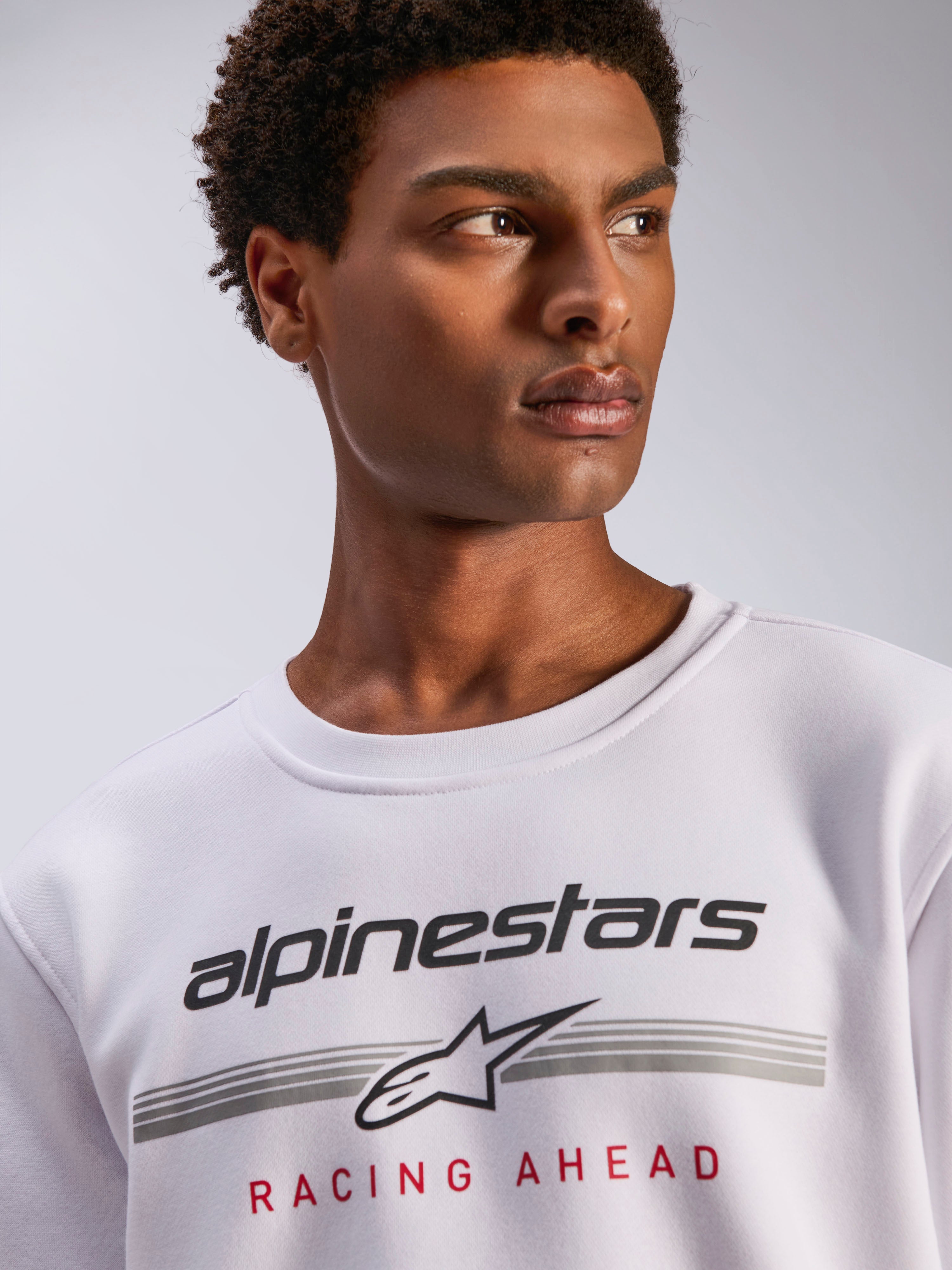 Alpinestars Bettern Crew, vit sweatshirt i fleece med rund hals, svart Alpinestars-logotyp med grå horisontella linjer och röd 'Racing Ahead'-text, avslappnad motorsportinspirerad streetwear