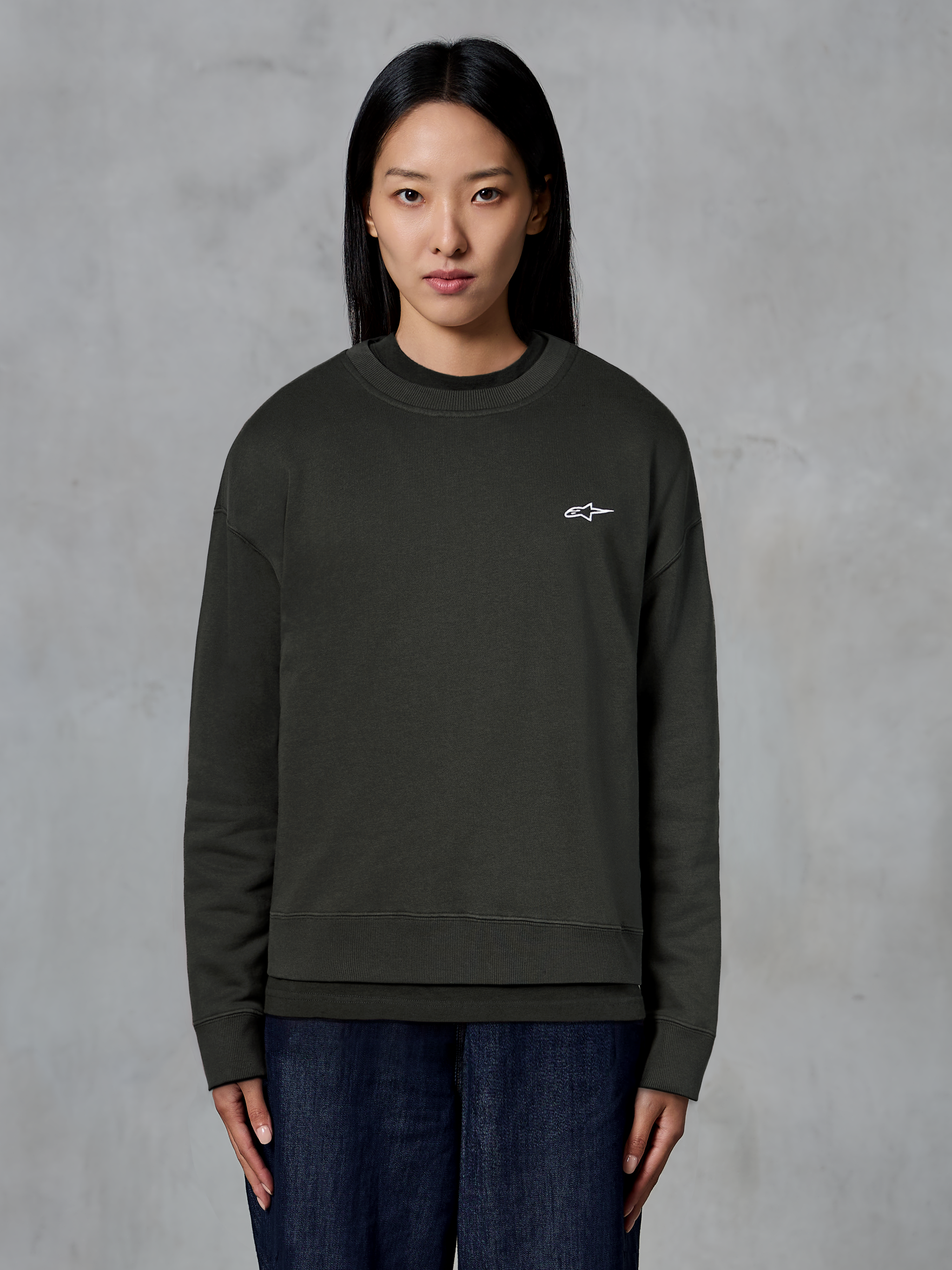 Alpinestars Essentials Ageless Crew, premium crewneck sweatshirt, Off Black, featuring a small white Alpinestars logo on the chest, casual streetwear style worn by a model with dark jeans